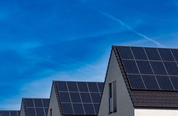 Zeitgenössische Häuser mit Solaranlagen unter einem strahlend blauen Himmel, die erneuerbare Energie fördern.