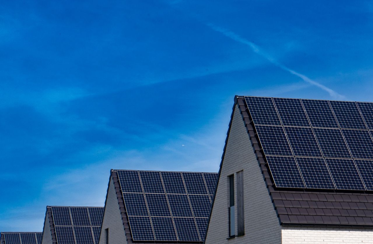 Zeitgenössische Häuser mit Solaranlagen unter einem strahlend blauen Himmel, die erneuerbare Energie fördern.