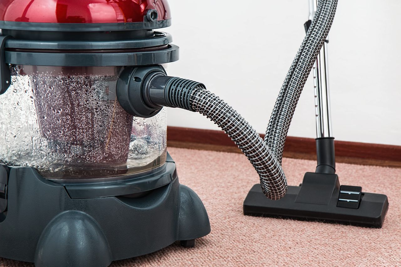 Nahaufnahme eines modernen Staubsaugers mit Wasserfilter auf einem Teppichboden in Innenräumen.