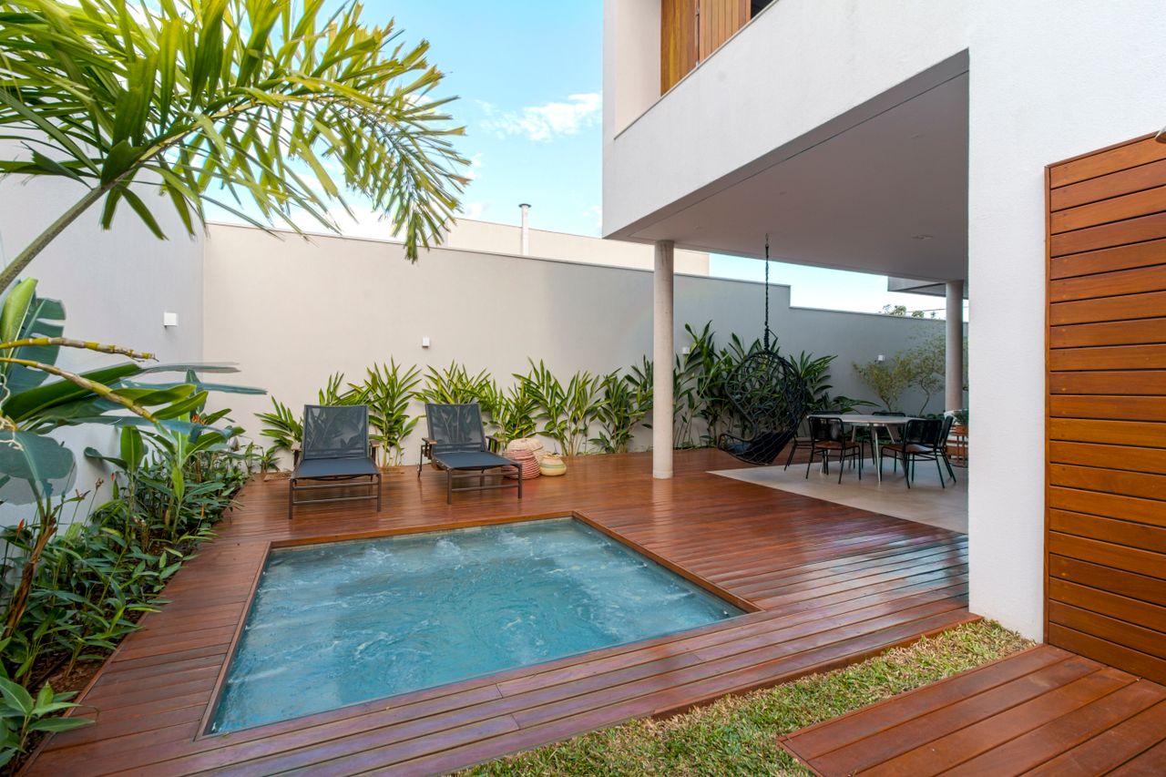 Eine ruhige moderne Terrasse mit einem luxuriösen Jacuzzi, schicker Möbeln und üppigem Grün.