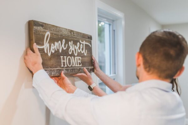 Ein Paar hängt ein 'Home Sweet Home'-Schild auf