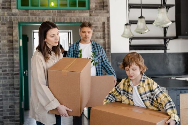 Familie, die Pappkartons trägt, während sie in ein neues Zuhause zieht.